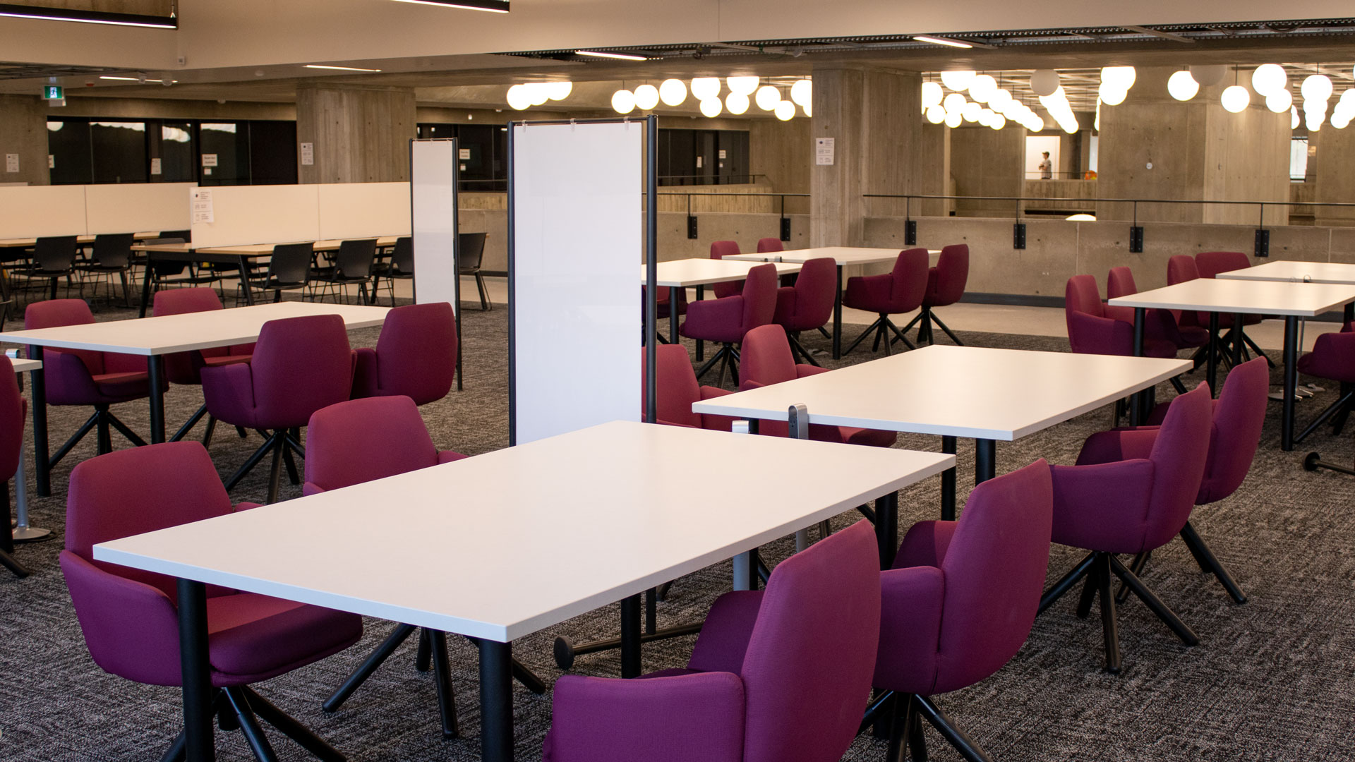 A group study area on Weldon Library Mezzanine with comfortable chairs around large tables and moveable whiteboards.