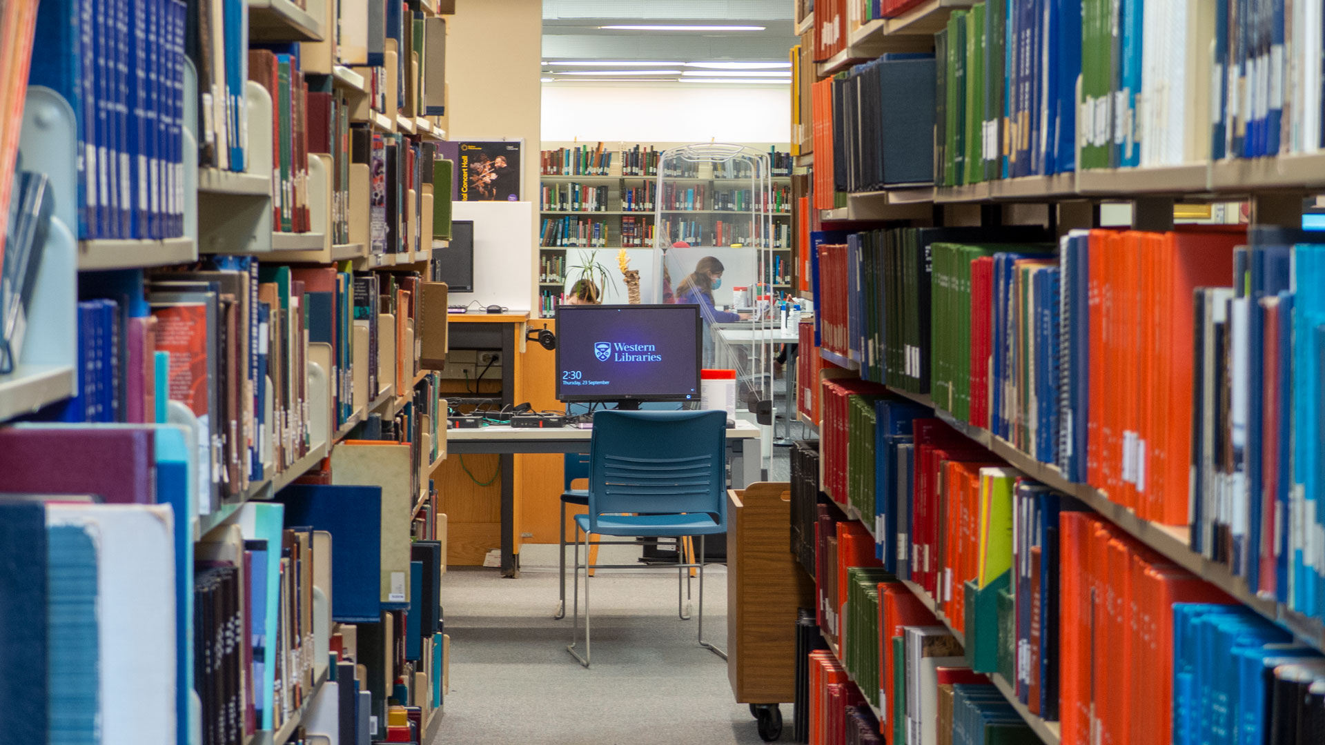 A computer terminal at end of an aisle of book stacks in the Music Library.